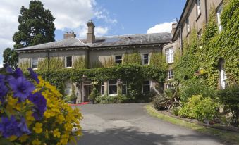 a large house surrounded by a lush garden , with a driveway leading up to it at St Andrews Town Hotel