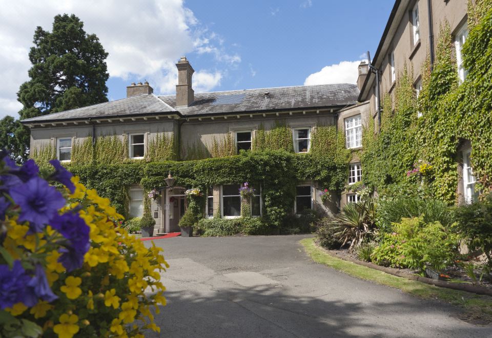 a large house surrounded by a lush garden , with a driveway leading up to it at St Andrews Town Hotel