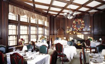 a large dining room with wooden tables and chairs , white tablecloths , and a wreath decoration on the ceiling at Castle Hill Resort and Spa