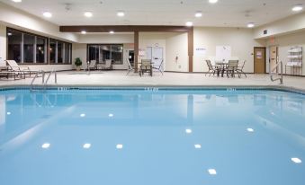 an indoor swimming pool with clear blue water , surrounded by white walls and equipped with chairs and tables at Country Inn & Suites by Radisson, Sidney, NE