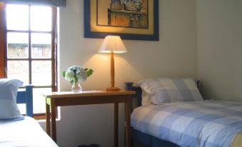 a cozy bedroom with two twin beds , a window , and a painting on the wall at MRS Simpson