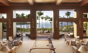 a large , open room with a table and chairs in the middle , surrounded by windows overlooking the ocean at Four Seasons Resort Lana'i