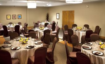 a well - decorated banquet hall with tables set for a formal event , featuring wine glasses and tablecloths at Hotel-Musee Premieres Nations