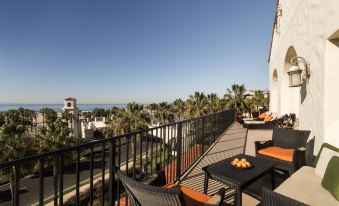 a rooftop terrace with a dining table and chairs , surrounded by palm trees and overlooking the ocean at Hyatt Regency Huntington Beach Resort and Spa