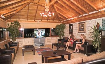a cozy living room with two women sitting on couches and a television mounted on the wall at Havana Hotel