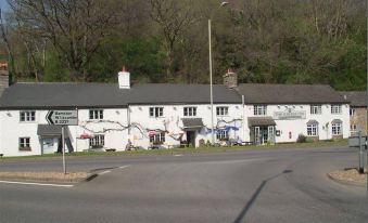 a white building with a gray roof and graffiti on the side , located on the side of a road at The Exeter Inn