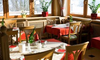 a dining room with several tables and chairs arranged for a group of people to enjoy a meal together at Hotel Königsblick by Keyone