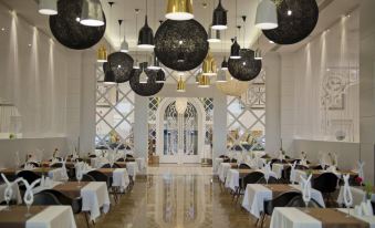 a large dining room with numerous tables and chairs arranged for a group of people at Q Premium Resort Hotel