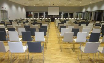 an empty conference room with rows of chairs and a large screen at the front at Cosmopolitan Hotel