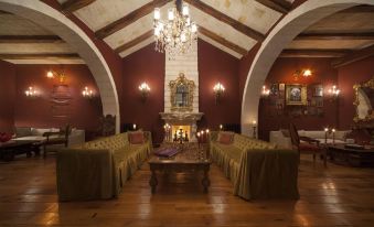 a cozy living room with wooden floors , red walls , and a fireplace , decorated with elegant furniture and chandeliers at Sacred House