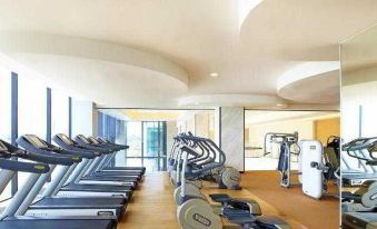 The gym is equipped with multiple treadmills and ellipticals positioned in front of large windows at Four Points by Sheraton Kuching