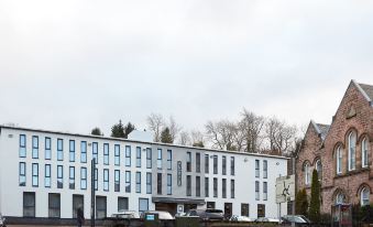 a modern building with a large parking lot and people walking in front of it at The Garrison