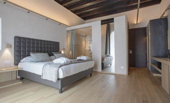 a modern bedroom with hardwood floors , a large bed , and a bathroom in the background at Alba Palace Hotel