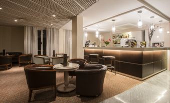 a modern bar with dark brown leather chairs , round tables , and white columns , as well as a bar counter with bottles at FlyOn Hotel & Conference Center