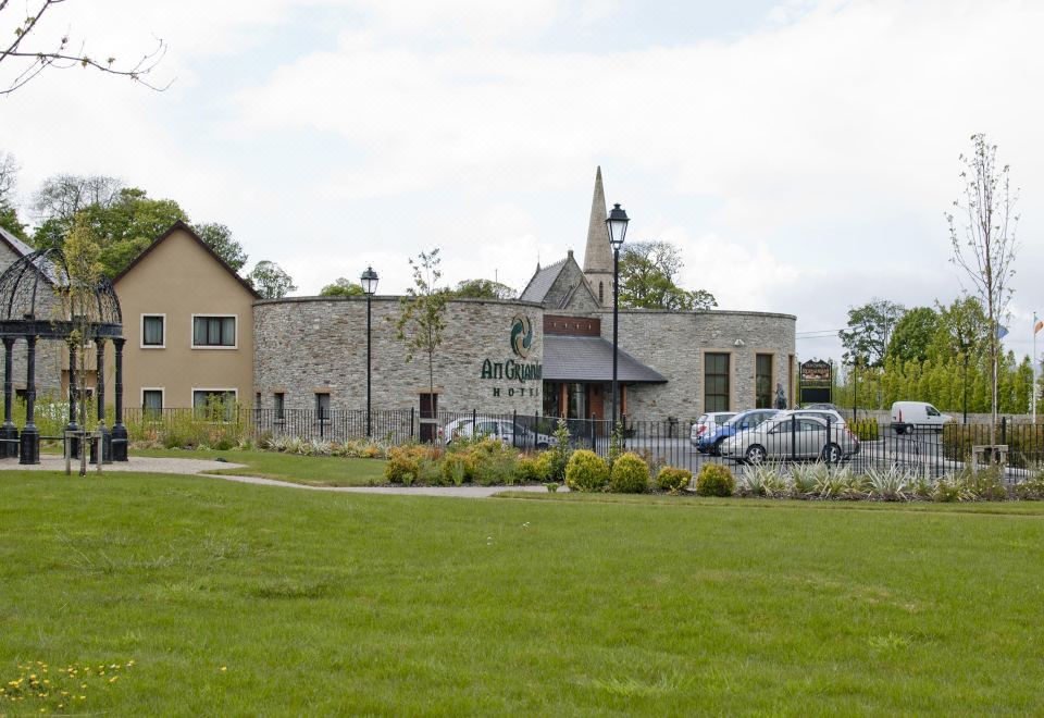 "a large building with a sign that reads "" hotel "" is surrounded by green grass and trees" at An Grianan Hotel