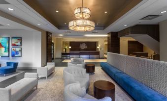 a modern hotel lobby with white couches , chairs , and a large chandelier hanging from the ceiling at Holiday Inn Chicago North-Evanston, an IHG Hotel