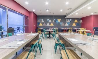 a modern , minimalist restaurant interior with wooden tables and chairs , red walls decorated with triangular patterns , and large windows at Novus Plaza Hodelpa