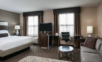 a hotel room with a king - sized bed , a desk , a chair , and a tv . also a bathroom nearby at Residence Inn by Marriott Boston Needham