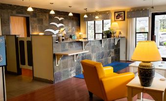 a cozy living room with a yellow chair and a bar counter , creating a comfortable atmosphere at Seabird Lodge Fort Bragg