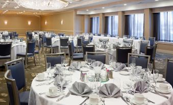 a large banquet hall filled with round tables and chairs , all set for a formal dinner at DoubleTree by Hilton Hotel Syracuse