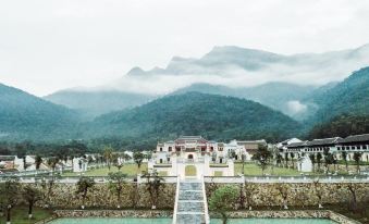 a beautiful village surrounded by mountains , with a stone pathway leading to a building and a bridge over a river at Legacy Yen Tu - MGallery