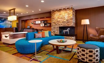 a living room with a blue couch , coffee table , and a fireplace in the background at Comfort Suites