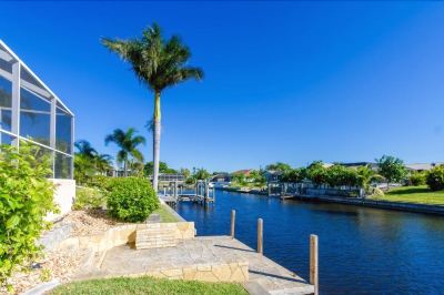 a serene waterfront scene with palm trees , houses , and a walkway leading to the water at Italy