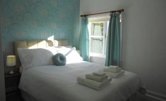 a white bed with blue sheets and towels , situated in a room with a window at The Old Post House