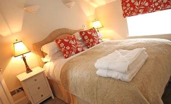 a well - decorated bedroom with a king - sized bed , white towels , and a lamp on the nightstand at Hare and Hounds