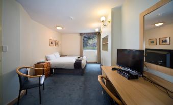 a hotel room with a king - sized bed , a flat - screen tv , and a desk with a computer at Jenolan Caves House