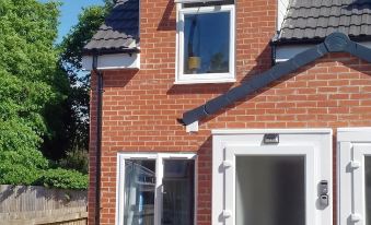 a brick house with a white door and window , located in a residential area with a fence surrounding it at The Nest