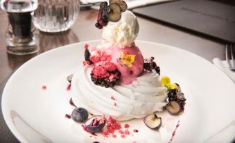 a white plate with a piece of cake on top , surrounded by various toppings and garnishes at The Sawley Arms