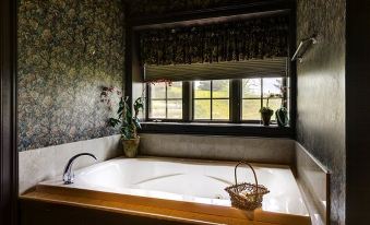 a bathroom with a large bathtub and a window , allowing natural light to fill the space at Claremont Inn & Winery