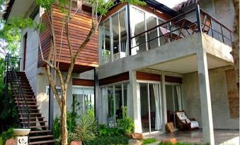 a large , modern house with a wooden deck and stairs leading up to the second floor at Suan Muang Porn