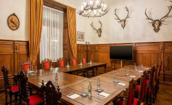 a large conference room with wooden tables , red chairs , and a chandelier , set up for an event at Schloss Lieser, Autograph Collection