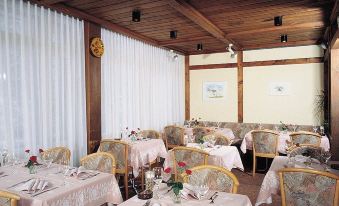 a dining room with a long table covered in a white tablecloth , surrounded by chairs at Hotel Residence