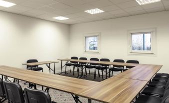 a large conference room with wooden tables and chairs arranged in a semicircle around a central table at Ibis Epinay Sur Seine - Gennevilliers