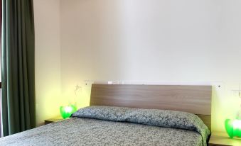 a bed with a blue patterned comforter and pillows is next to a green light on the wall at Dora