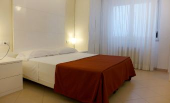 a large bed with a red blanket is in a room with white walls and curtains at Nautilus