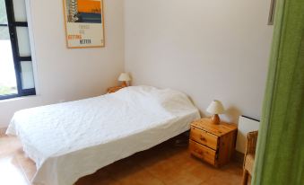 a white bed with a white sheet is in a room with a wooden nightstand and a window at Holiday Home Villa Isabelle