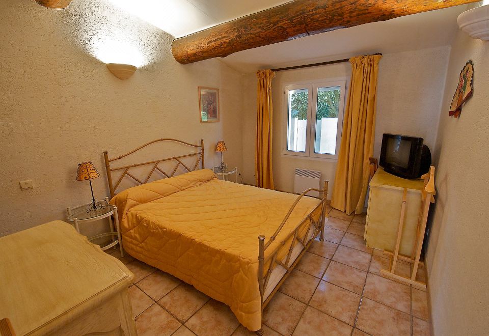 a cozy bedroom with a large bed , a tv , and a door leading to a balcony at Cucuron