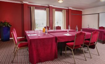 a conference room set up for a meeting , with several chairs arranged in a semicircle around a table at Garden Court Hotel Aylesbury