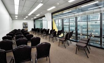 a conference room with rows of chairs arranged in a semicircle , and a yellow flag hanging on the wall at Pegasus Apart'Hotel