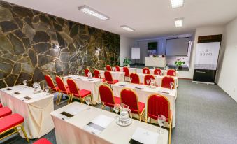 a conference room with rows of chairs and tables set up for a meeting or event at Hotel Royal
