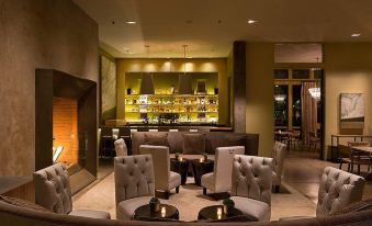 a modern bar area with several chairs and couches arranged around a fireplace , creating a cozy atmosphere at Hotel Healdsburg