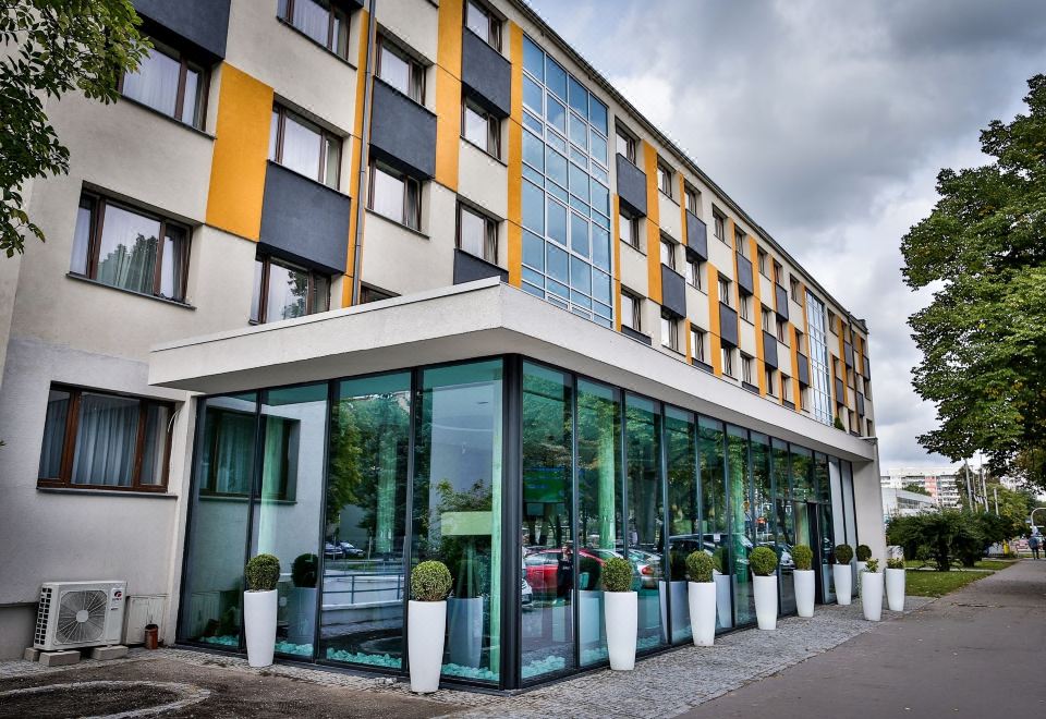 a modern building with a glass facade and yellow and white accents , surrounded by potted plants at Boutique Hotel's