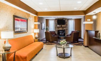 a living room with an orange couch , two chairs , and a television mounted on the wall at Comfort Suites Lewisburg