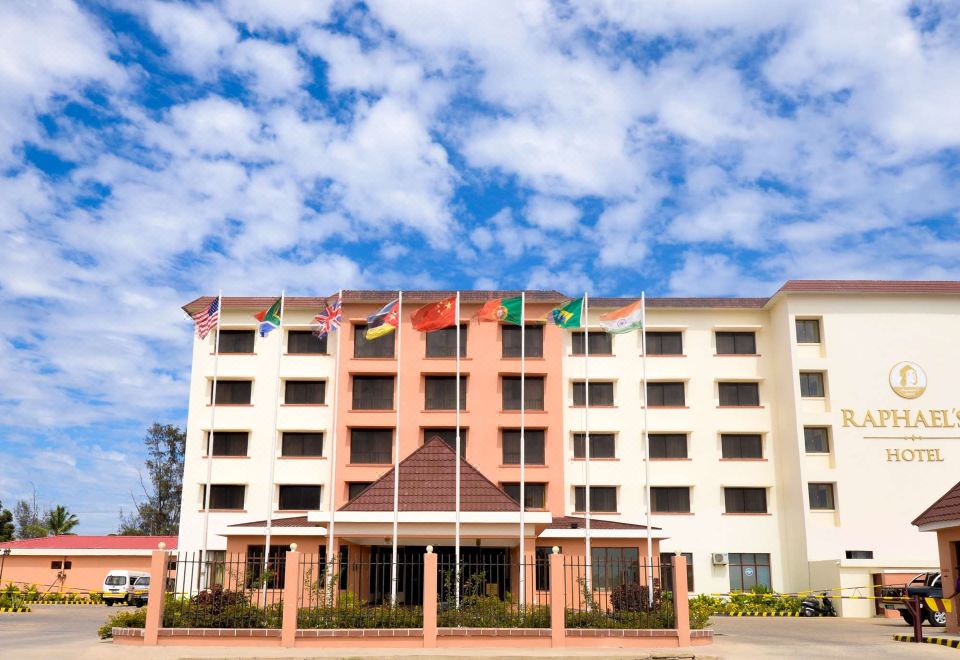 a large building with flags flying in front of it , under a cloudy blue sky at Raphael's Hotel