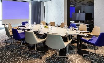 There is a spacious conference room furnished with blue chairs and a long table that can accommodate up to 10 people at Remis Hotel
