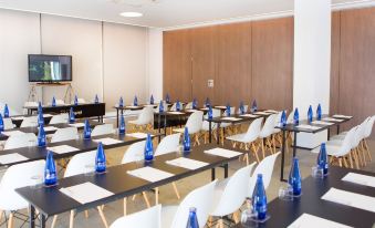 a conference room set up for a meeting , with tables and chairs arranged in rows at Hotel Cap Negret